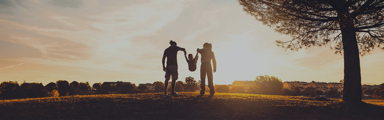 A mother and father in a park lifting their child.